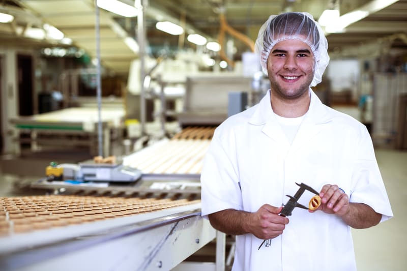 Un apprendista tecnico alimentarista misura le dimensioni di un biscotto