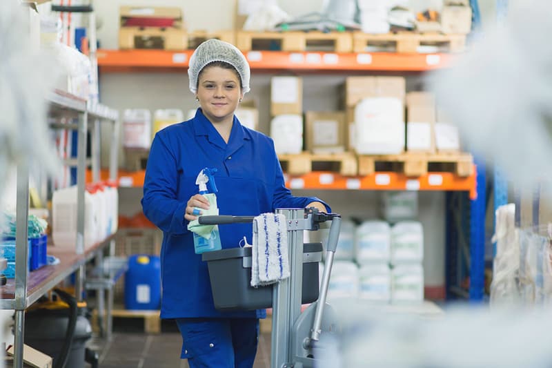 Un'apprendista addetta d'economia domestica con il carrello delle pulizie