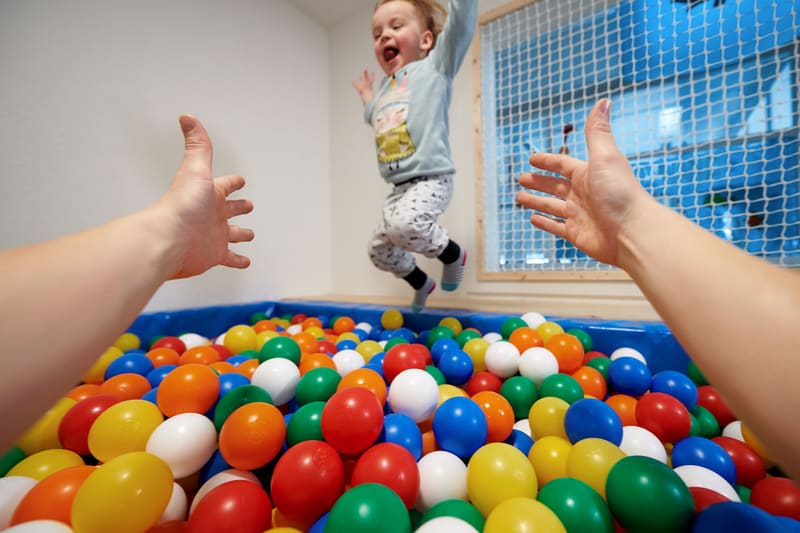 Un bambino salta in una piscina di palline colorate