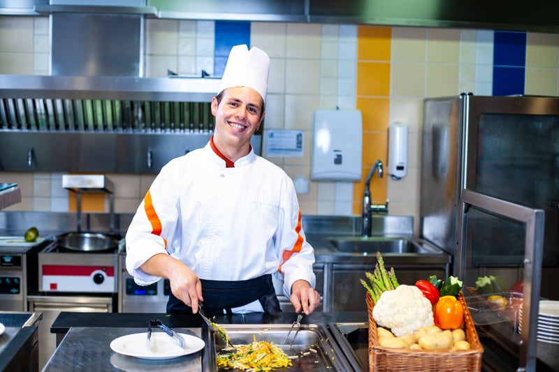 Un apprendista addetto di cucina frigge delle verdure