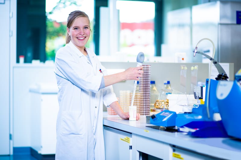 Un'apprendista laboratorista in biologia tiene un dispositivo di misurazione in un becher