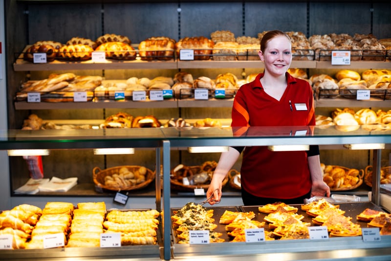 Un'apprendista impiegata del commercio al dettaglio (panetteria/pasticceria/confetteria) dietro al bancone