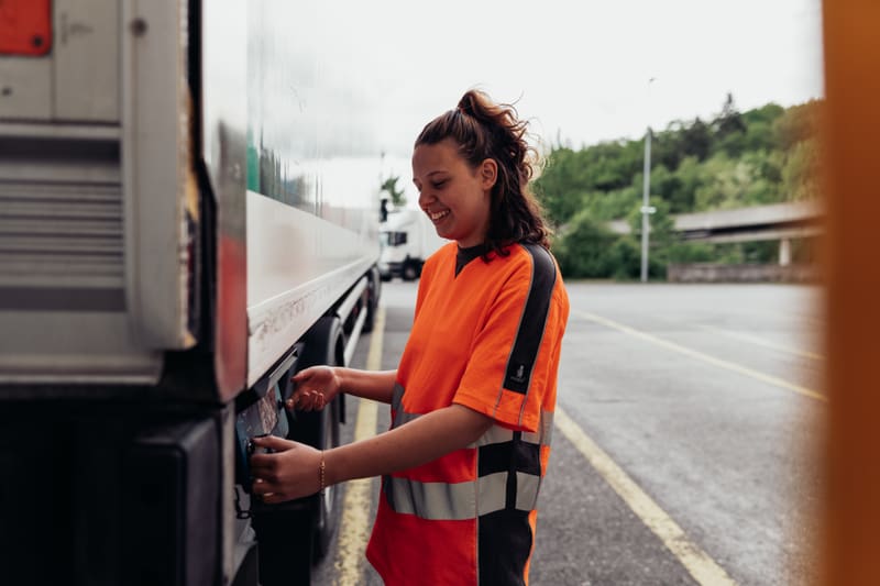 Junge Frau stellt etwas an LKW ein