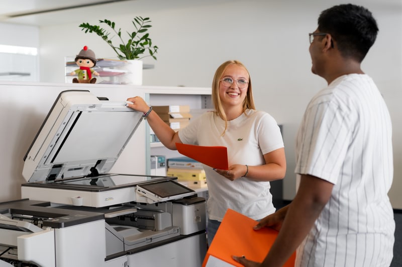 Frau und Mann verwenden Drucker und lachen