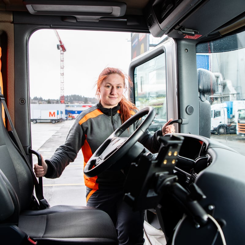Eine LKW-Chauffeurin steht in der Fahrertür eines Lastwagens.