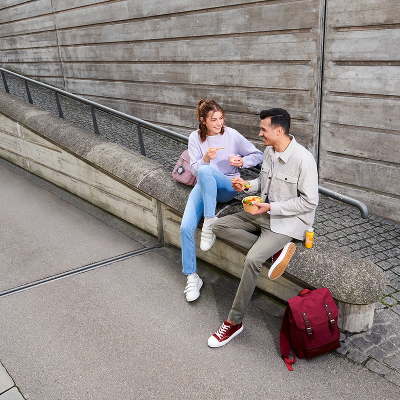 Zwei Personen sitzen an der Strasse