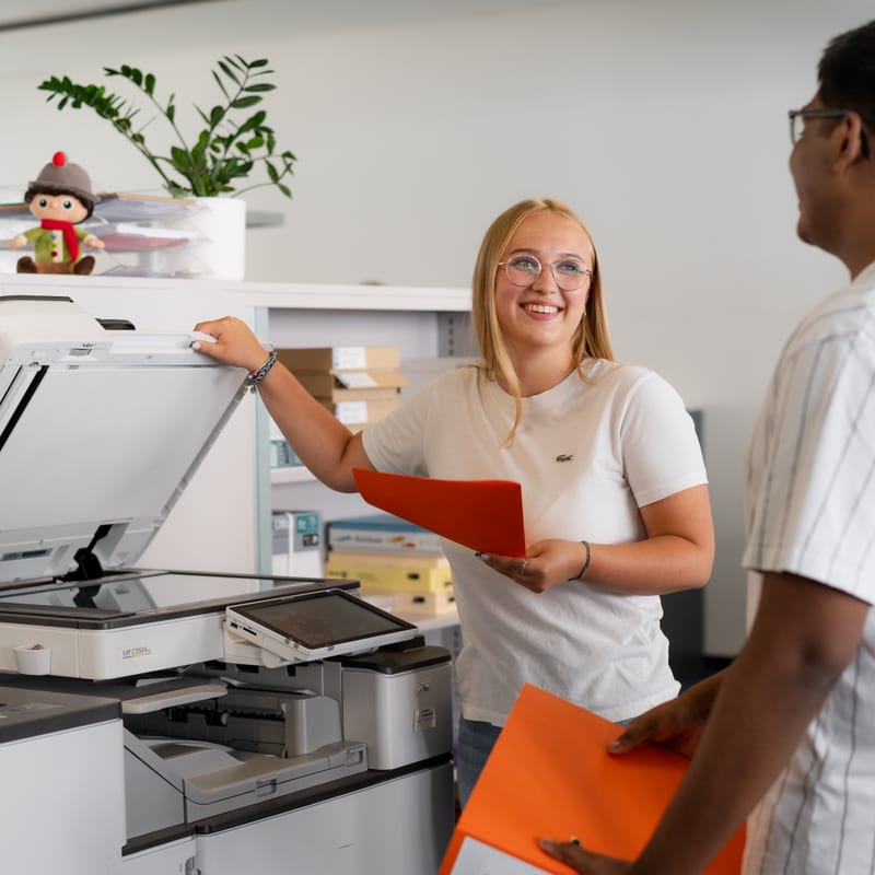 Frau und Mann verwenden Drucker und lachen