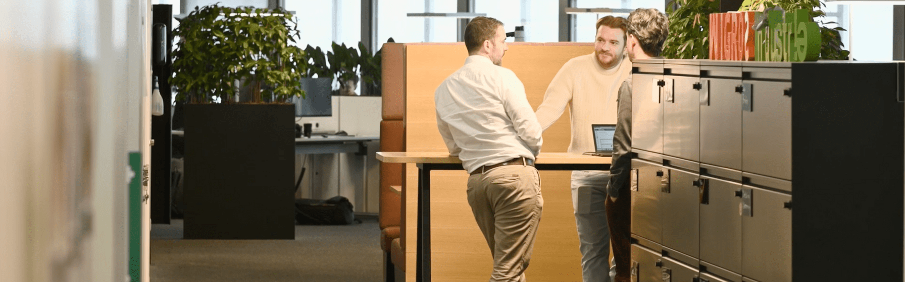 Drei Männer stehen an einem Arbeitstisch