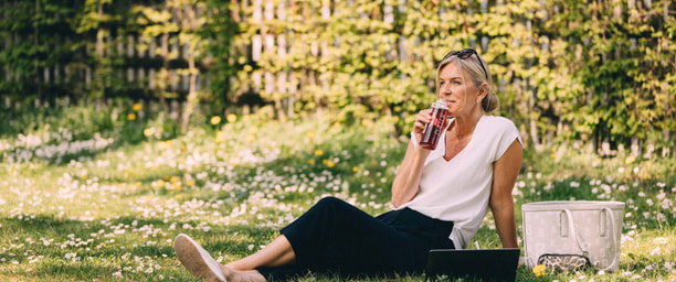 Frau auf einer Wiese am Trinken