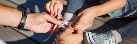 Mains faisant les lacets d'un enfant