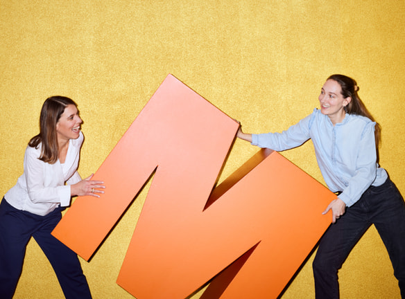 Zwei Mitarbeiterinnen halten ein grosses M